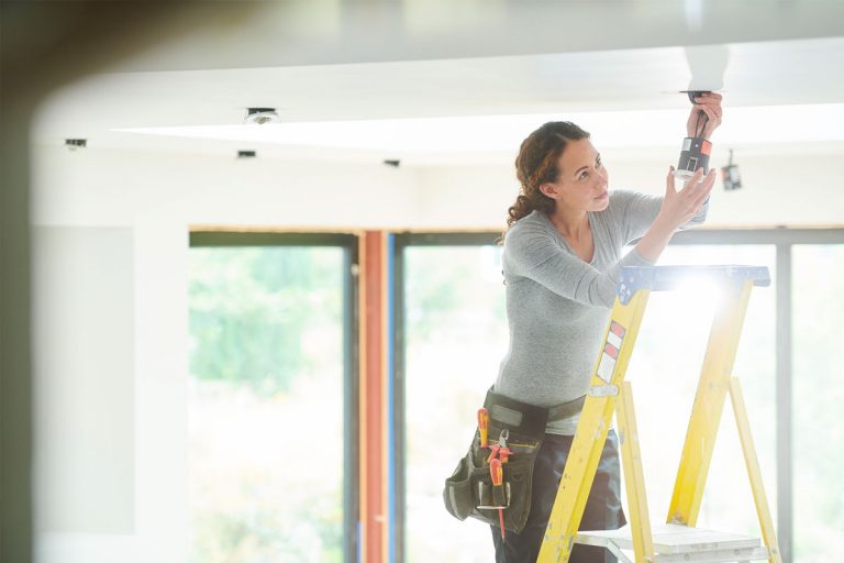 A woman installing a new light bulb.
