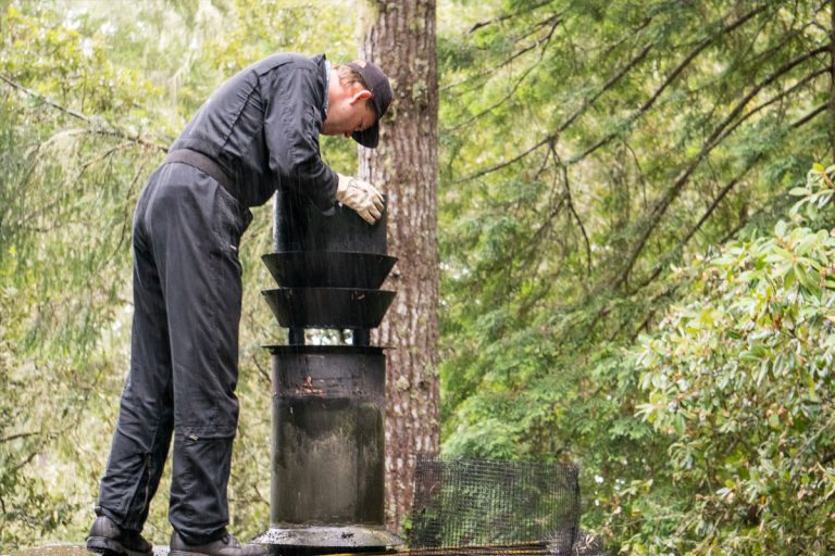 A chimney maintenance person looking down a chimney.