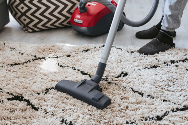 Someone vacuuming an area rug.