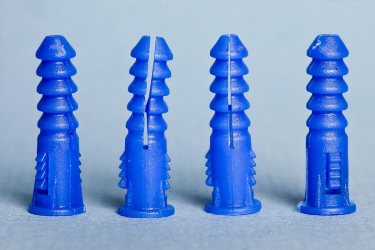 A line of four blue drywall anchors.