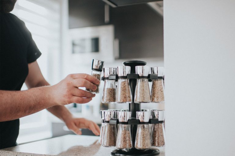 A person picking out a spice from a spice rack.