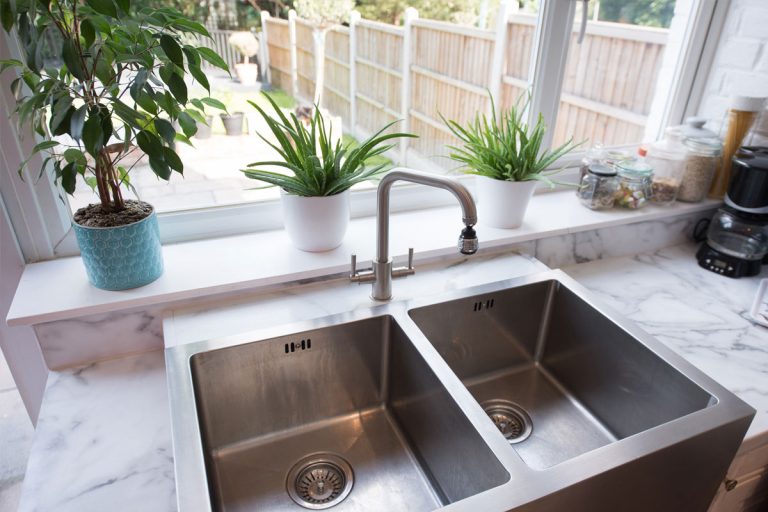A kitchen sink, in front of an open window