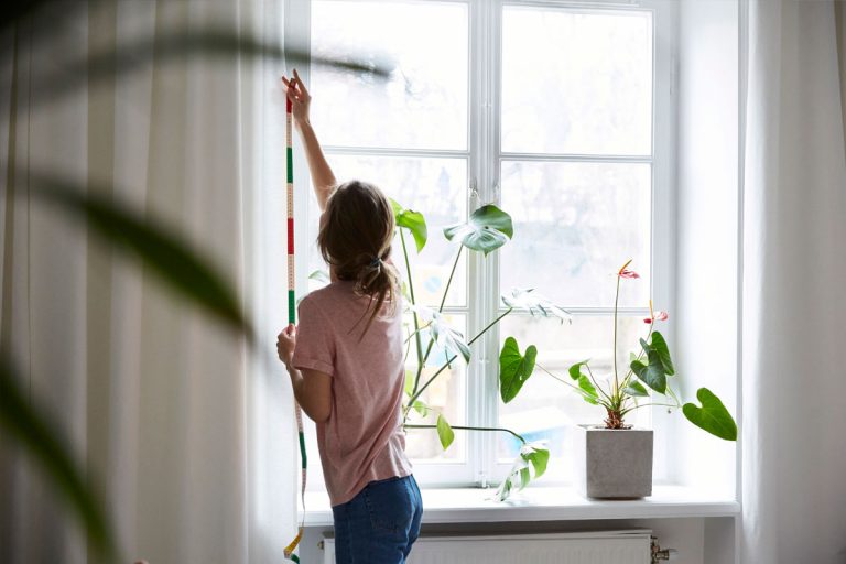 A woman measuring a window