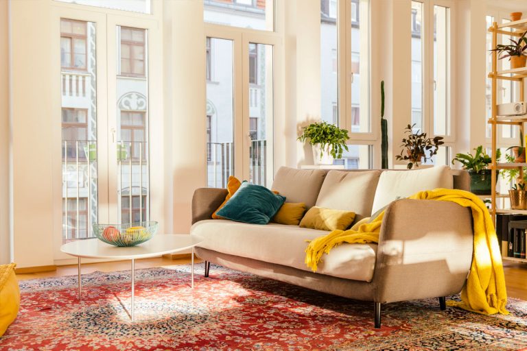 A yellow throw blanket on a tan couch in a living room.