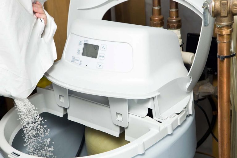 A person pouring a solution into a water softener system.