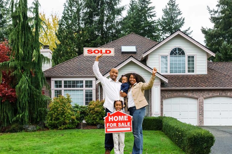 A family standing in front of a house with sold signs.